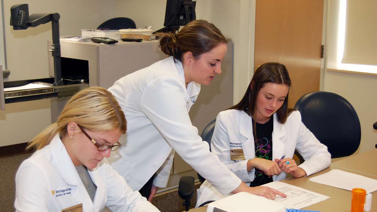 A pharmacy student examines equipment.