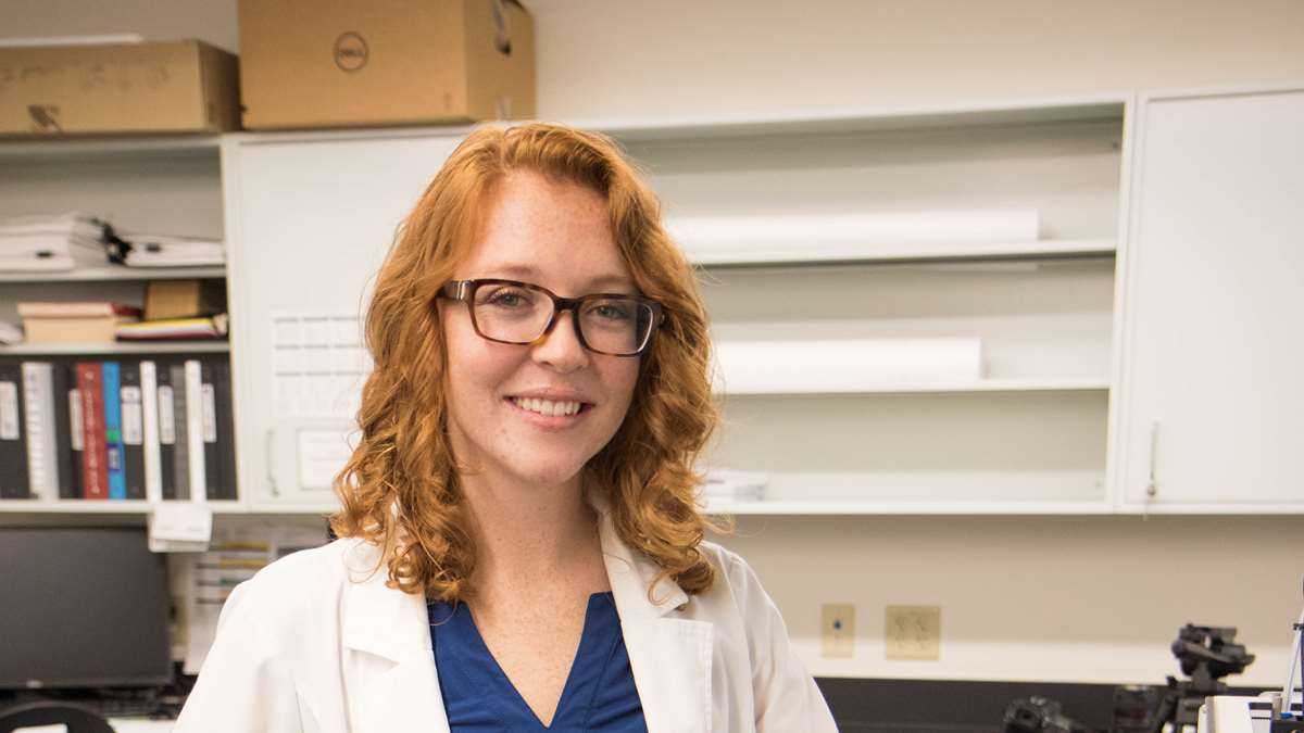 Courtney Burgazli stands by a 3D printer in a School of Pharmacy lab.