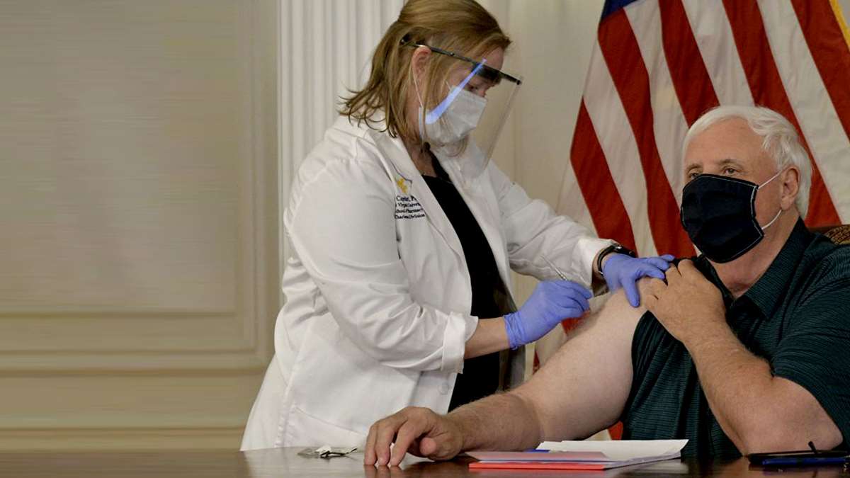 A photo of a pharmacist giving a man a vaccine.