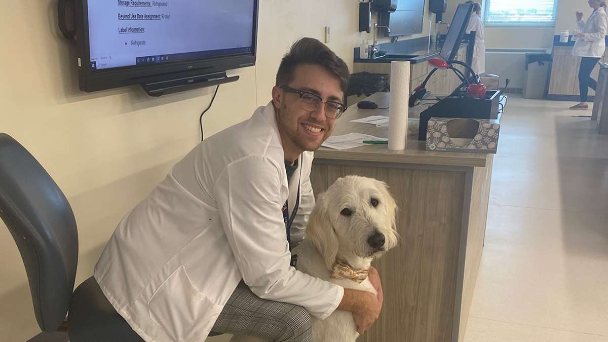 PharmD Candidate Brandon Harvey with Visitation Therapy Dog Titan.