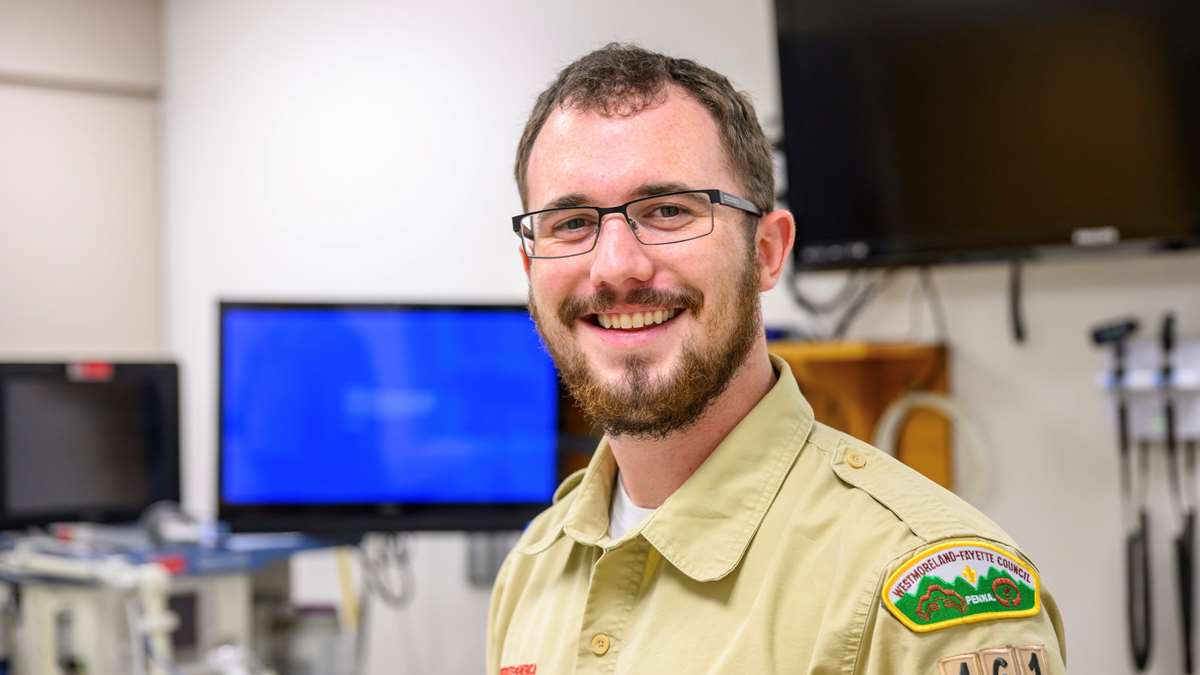 A male dressed in a Scout uniform poses for a photo.